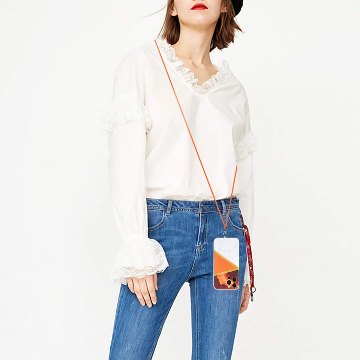 Frau mit weißer Bluse und Jeans hält ein Handy mit Lanyard. Telefon hat orange Akzente.