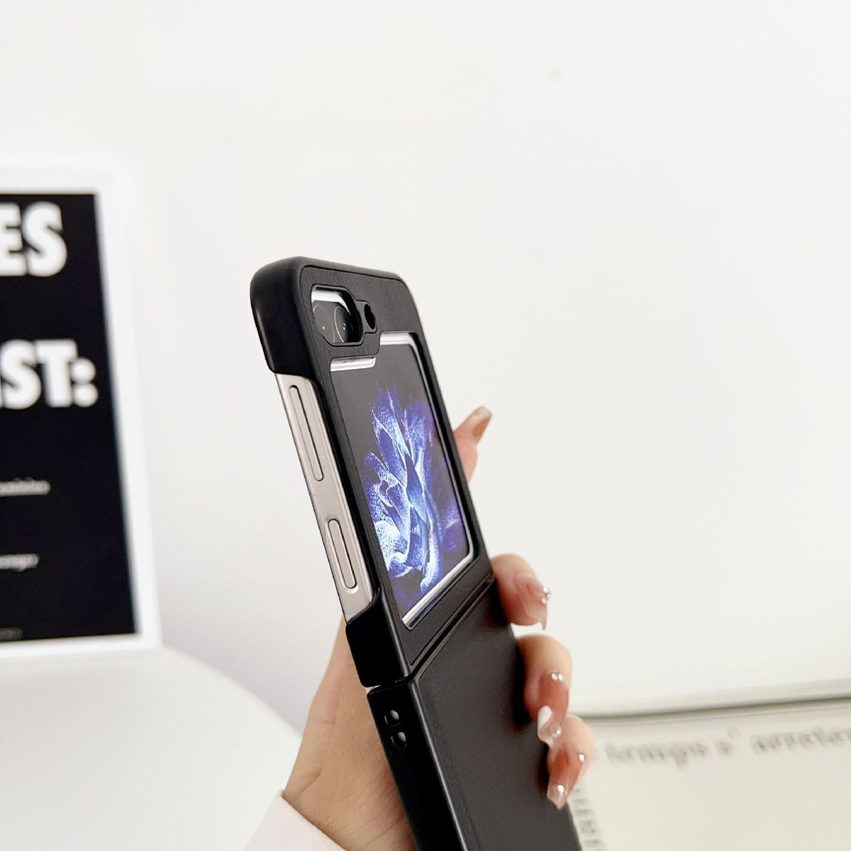 Hand hält schwarzes Telefon, Bildschirm sichtbar, in schwarzem Gehäuse.