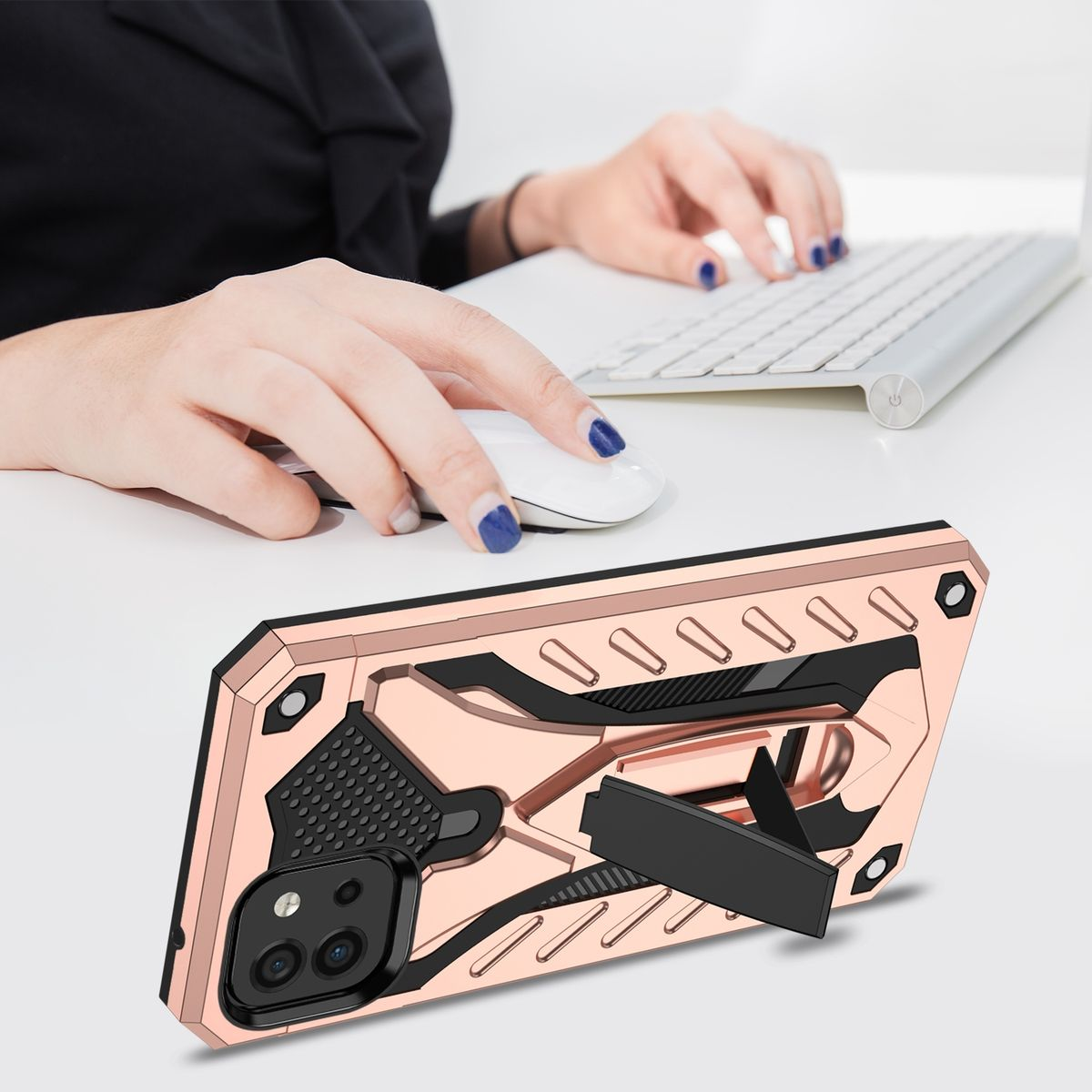 Hände arbeiten an einem Laptop. Eine roségoldene Handyhülle mit Ständer ist im Vordergrund. Blaue lackierte Nägel sind sichtbar.