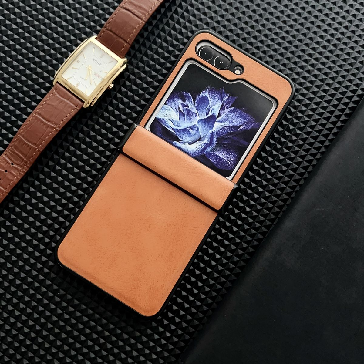 Eine Handyhülle mit braunem Cover, eine Uhr und ein schwarzer Hintergrund.