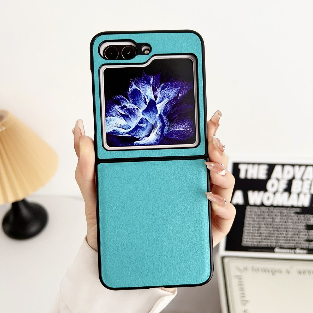 Türkisfarbene Handyhülle offen, mit Telefon, von Hand gehalten auf Weiß.