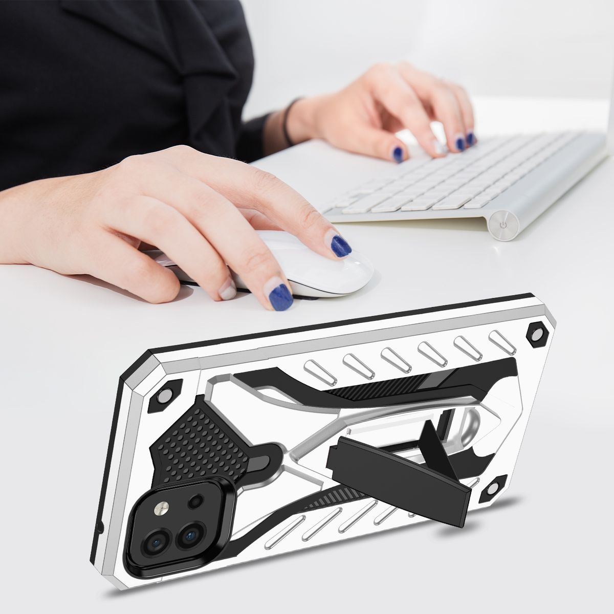 Hände benutzen Maus und Tastatur. Eine Handyhülle liegt auf dem Tisch mit ausgeklapptem Ständer.