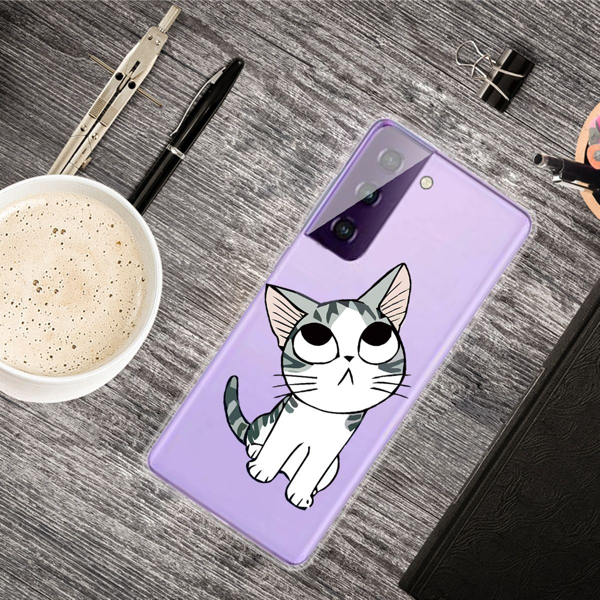 Ein Telefon mit Katzendesign liegt mit anderen Gegenständen auf einem Schreibtisch.