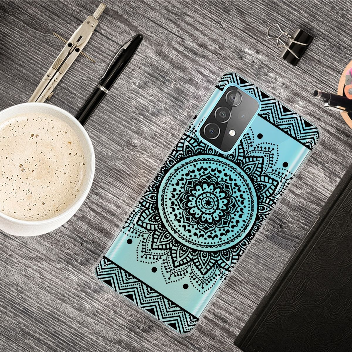 Handyhülle mit hellblauem Hintergrund und schwarzem Mandala-Design. Kaffee und Zubehör sind sichtbar.