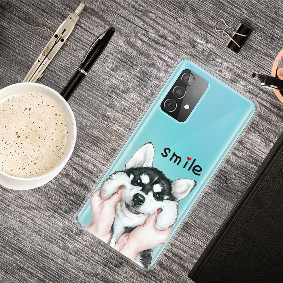 Eine Handyhülle mit einer Hundeillustration, mit dem Wort 'smile'. Zubehör auf dem Tisch.