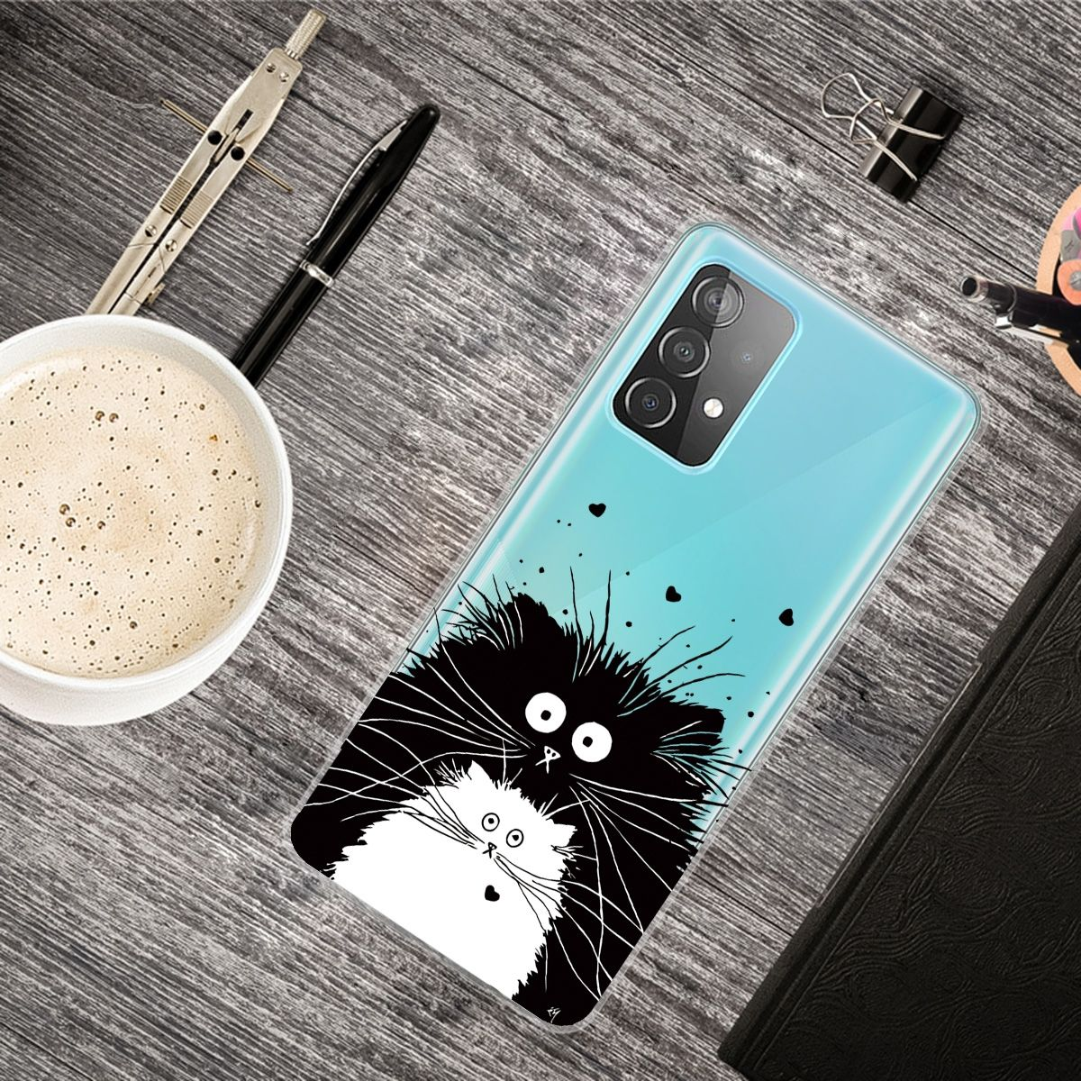 Handyhülle mit Katzendesign. Telefon liegt auf einem Holztisch. Es gibt eine Tasse Kaffee und einen Stift.