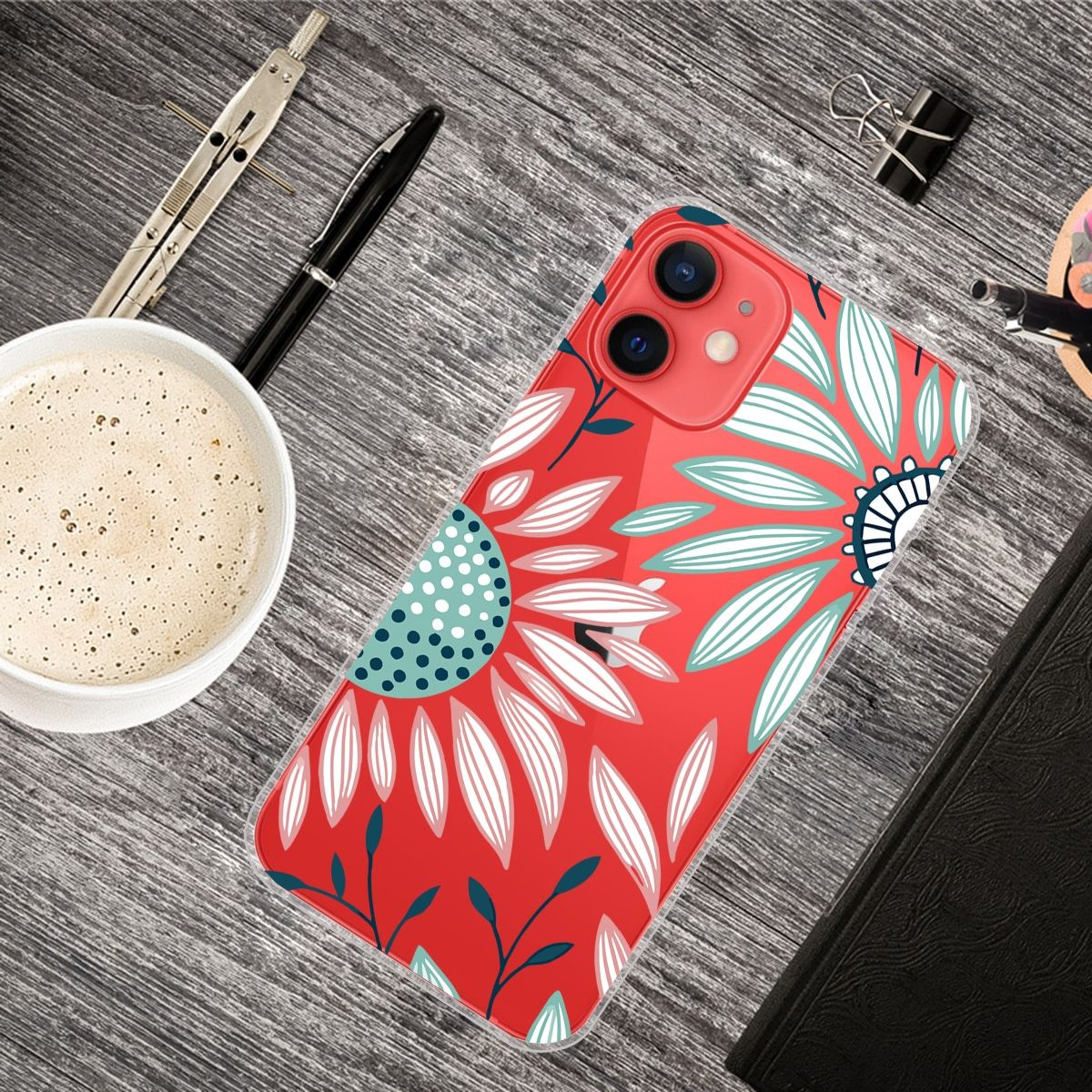 Handyhülle mit rotem Hintergrund und Blumendesign. Umgeben von Büromaterial und einer Kaffeetasse.