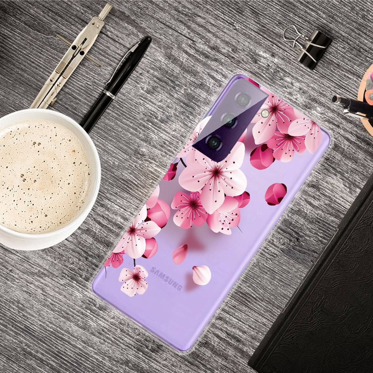 Telefon mit floralem Case auf einem Schreibtisch. Auf dem Schreibtisch sind eine Kaffeetasse, ein Stift und andere Gegenstände.