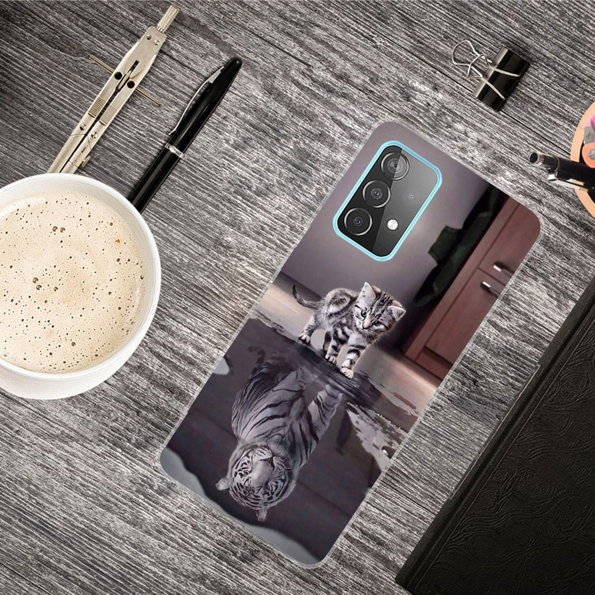 Eine Handyhülle mit einem Kätzchen-Reflex, mit Zubehör wie Stift, Kaffee und Notizblock.