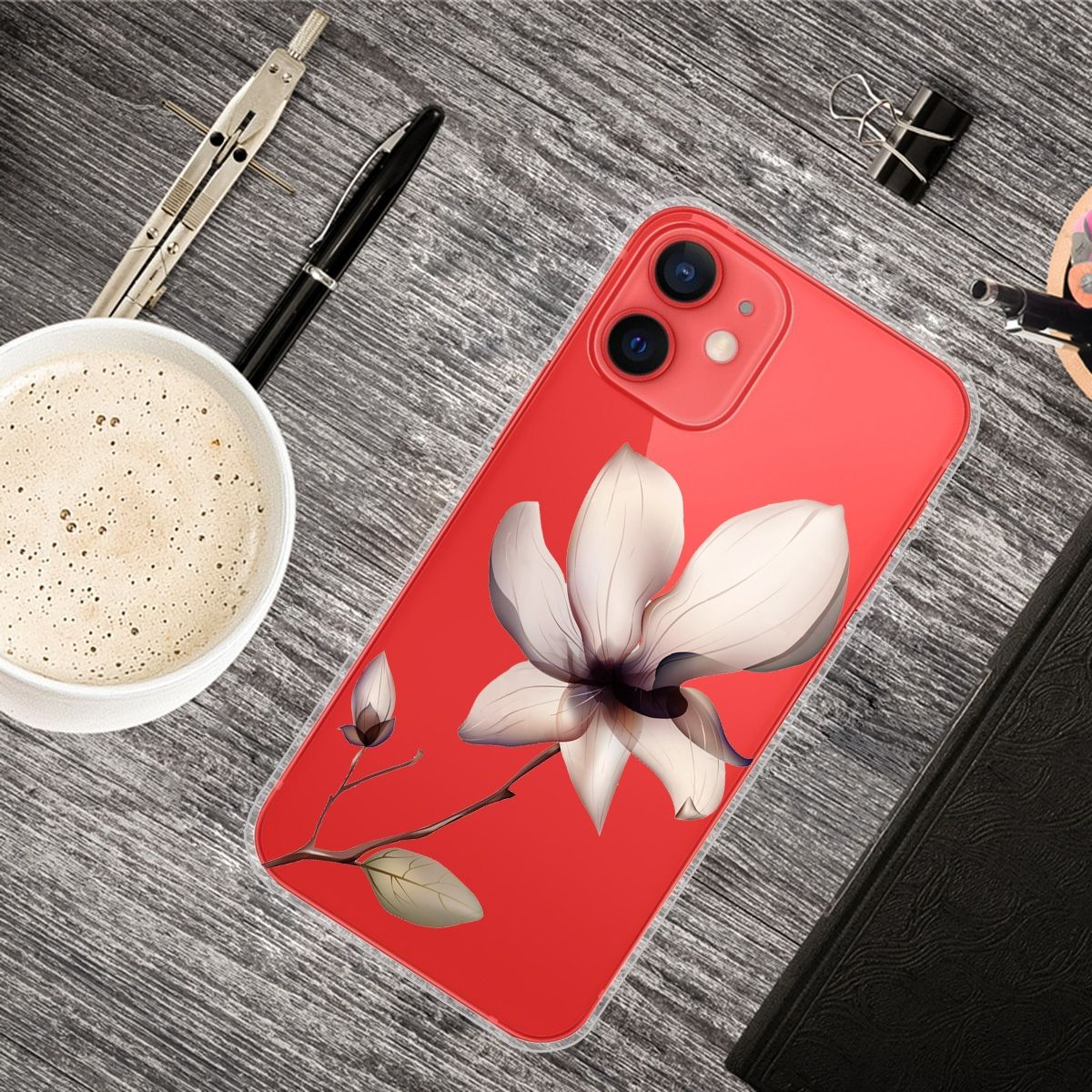 Eine Handyhülle mit Blumendesign auf einem Holztisch, umgeben von Stiften, Kaffee und Büromaterial.