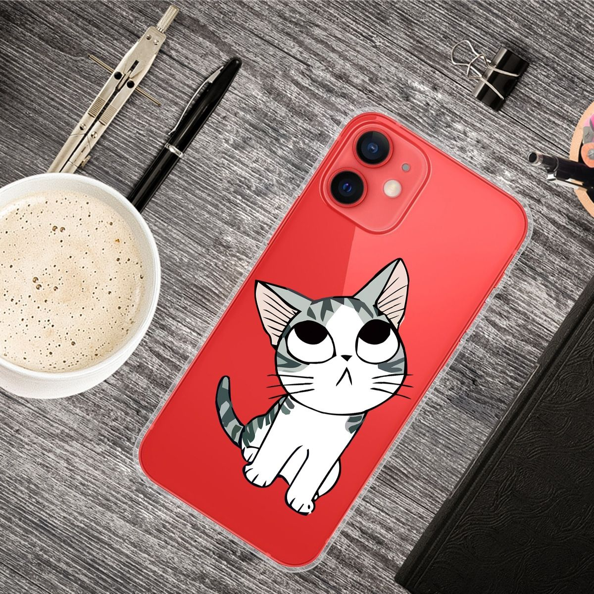 Ein Telefon in roter Hülle, auf einem Holztisch, mit einem Katzen-Cartoon auf der Rückseite.