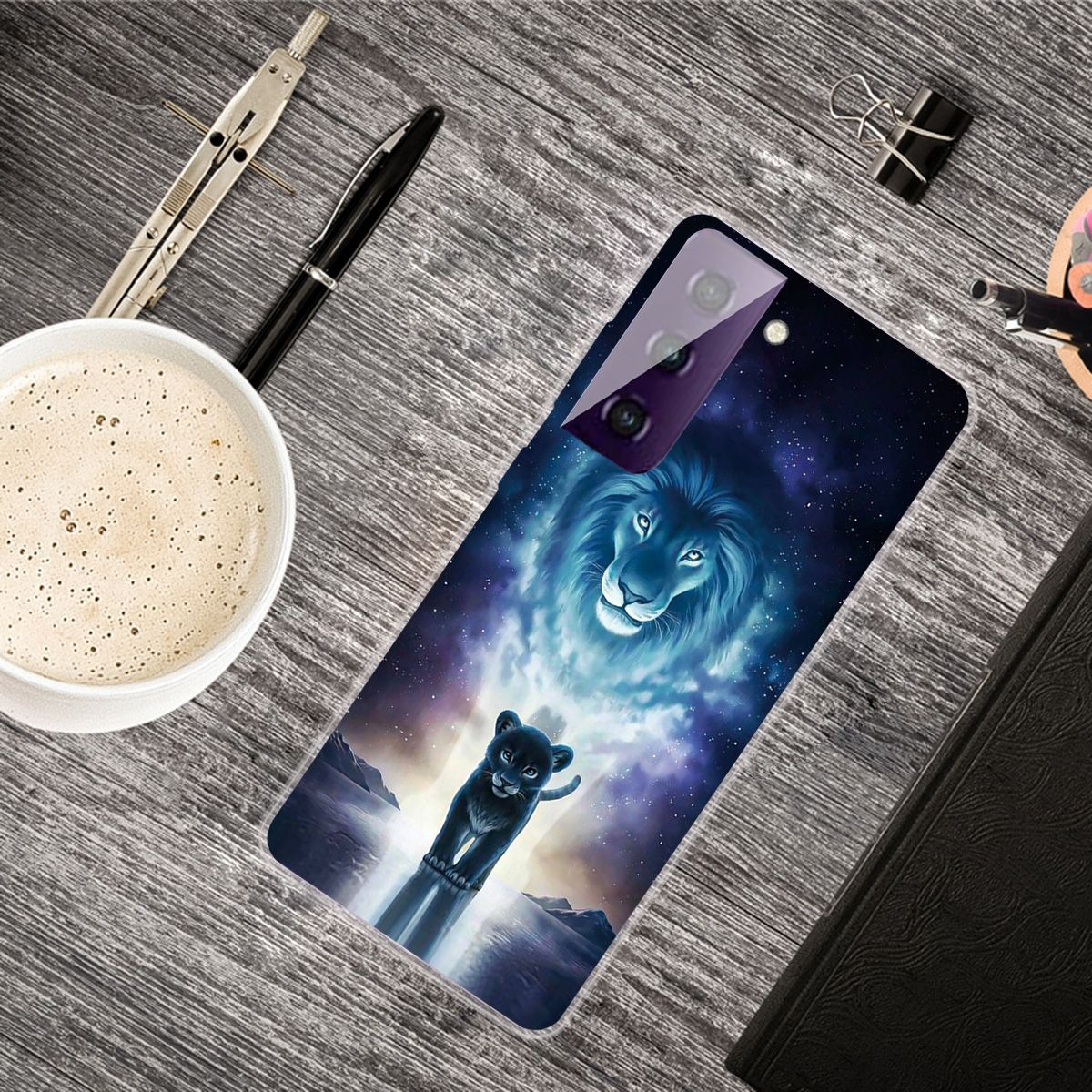 Handyhülle mit Löwen- und Jungtier-Design auf einem Schreibtisch mit Kaffeetasse und Zubehör.