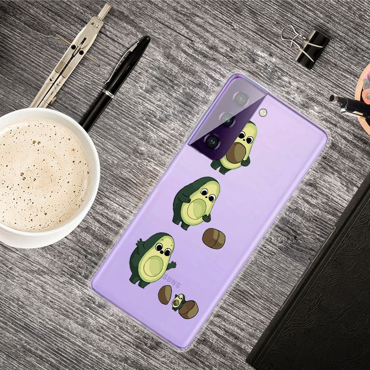 Handyhülle mit Avocado-Cartoonfiguren und anderen Objekten. Weißer Tischhintergrund.