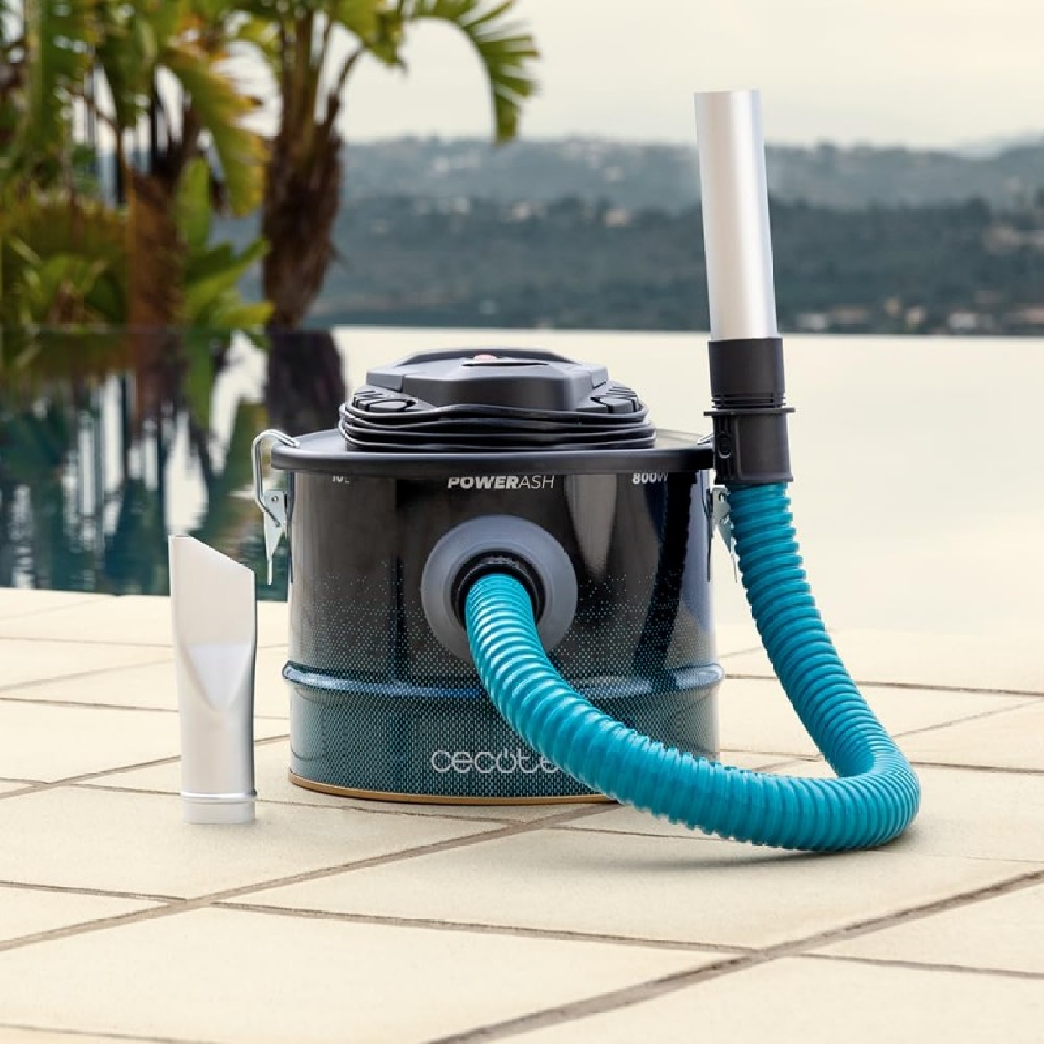 Aspirapolvere PowerAsh nero e verde acqua. Tubo acquamarina. Sfondo piscina e acqua.