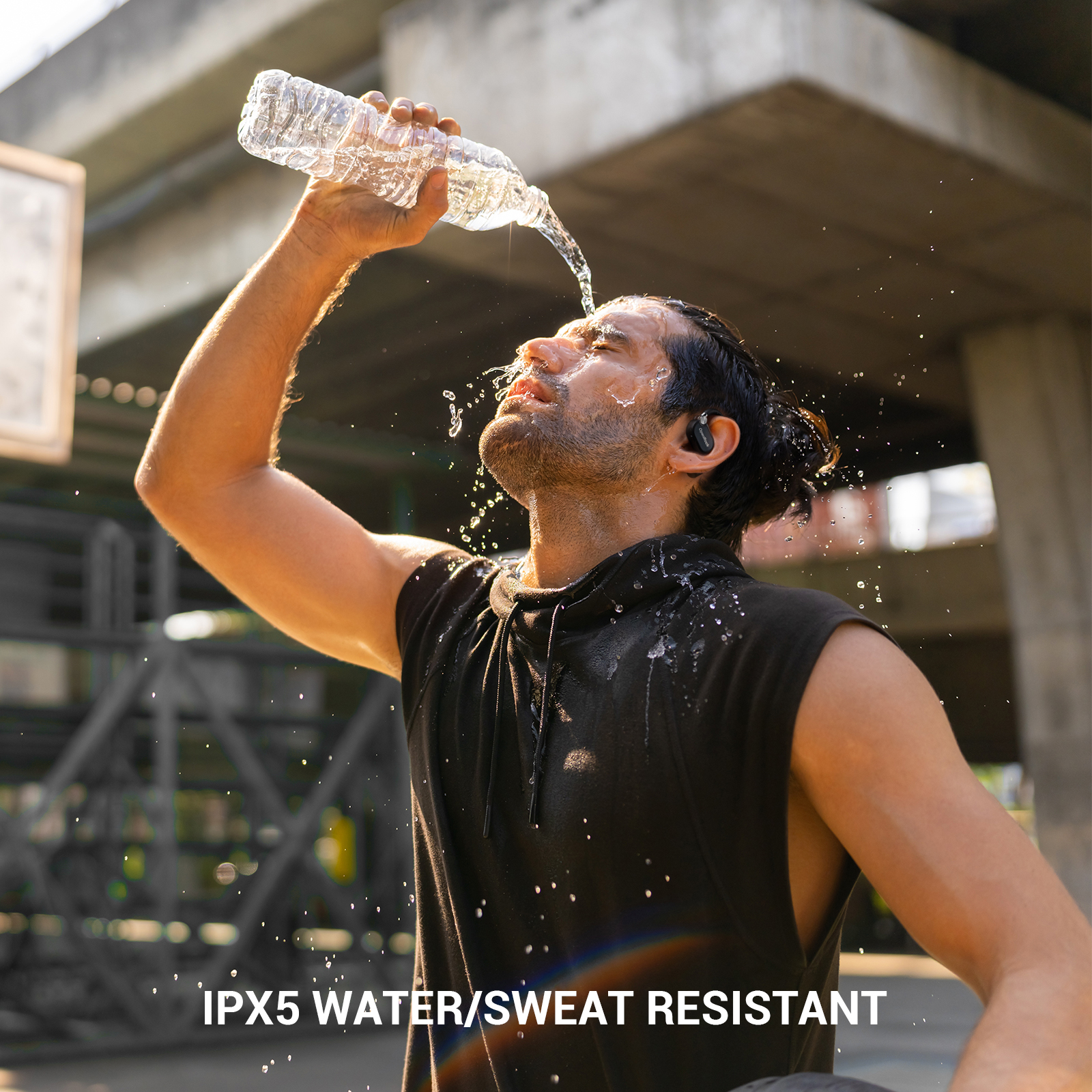 Man giet water over zijn hoofd terwijl hij oordopjes draagt. Tekst: IPX5 WATER/ZWEET BESTENDIG.