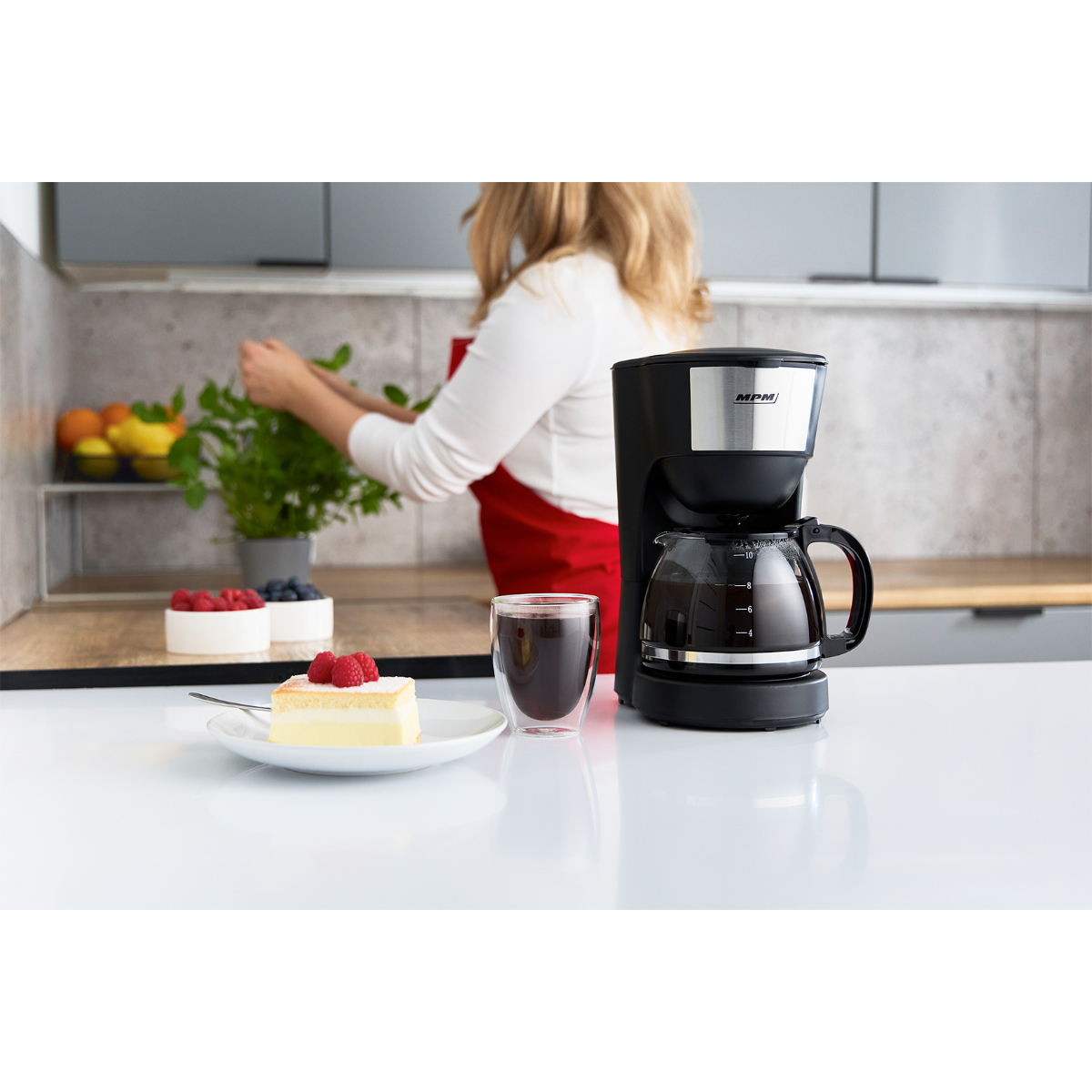 Ekspres do kawy z ciastem, jagodami i szklanką kawy.