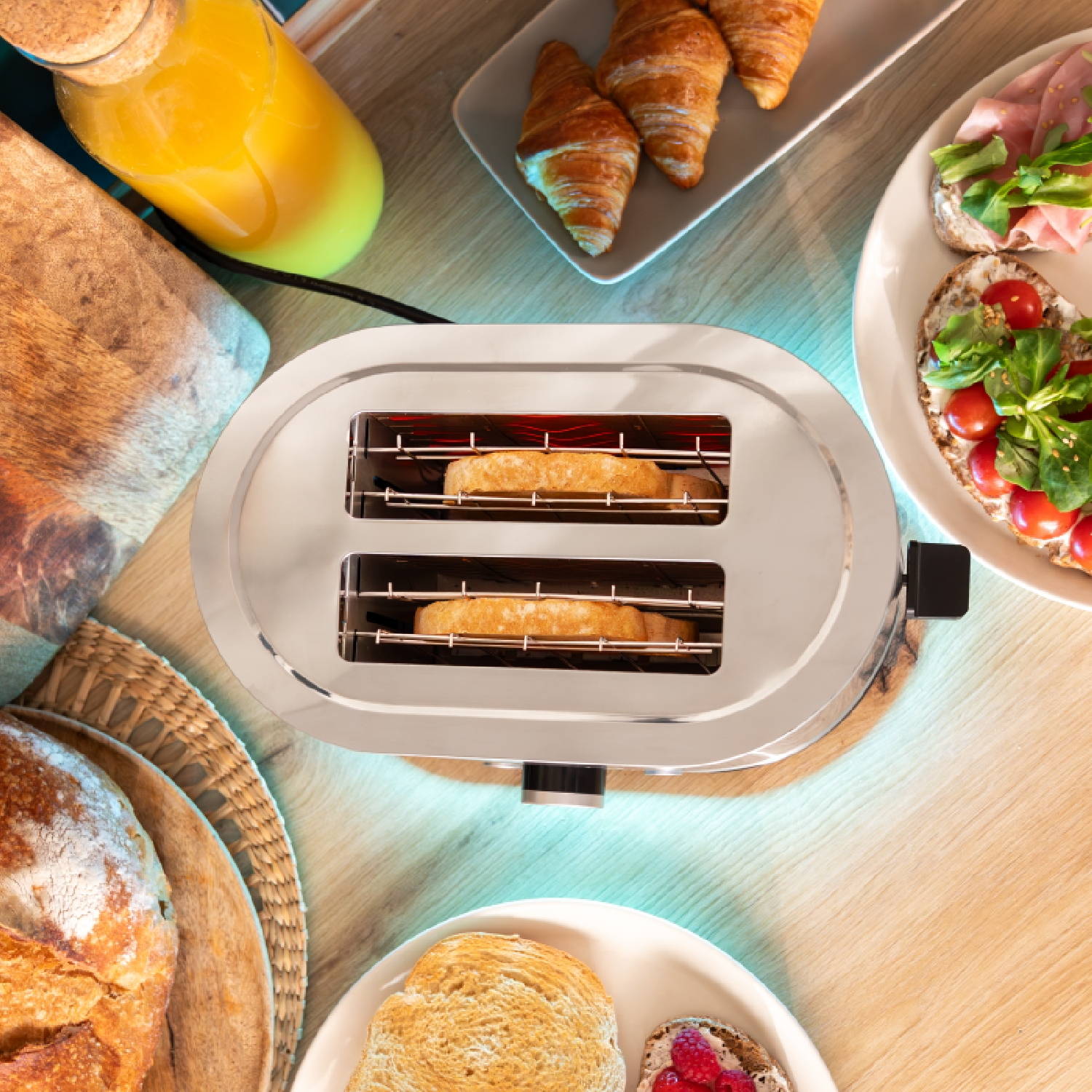 Ein Toaster mit Brot, Croissants und andere Frühstücksartikel auf einem Holztisch.