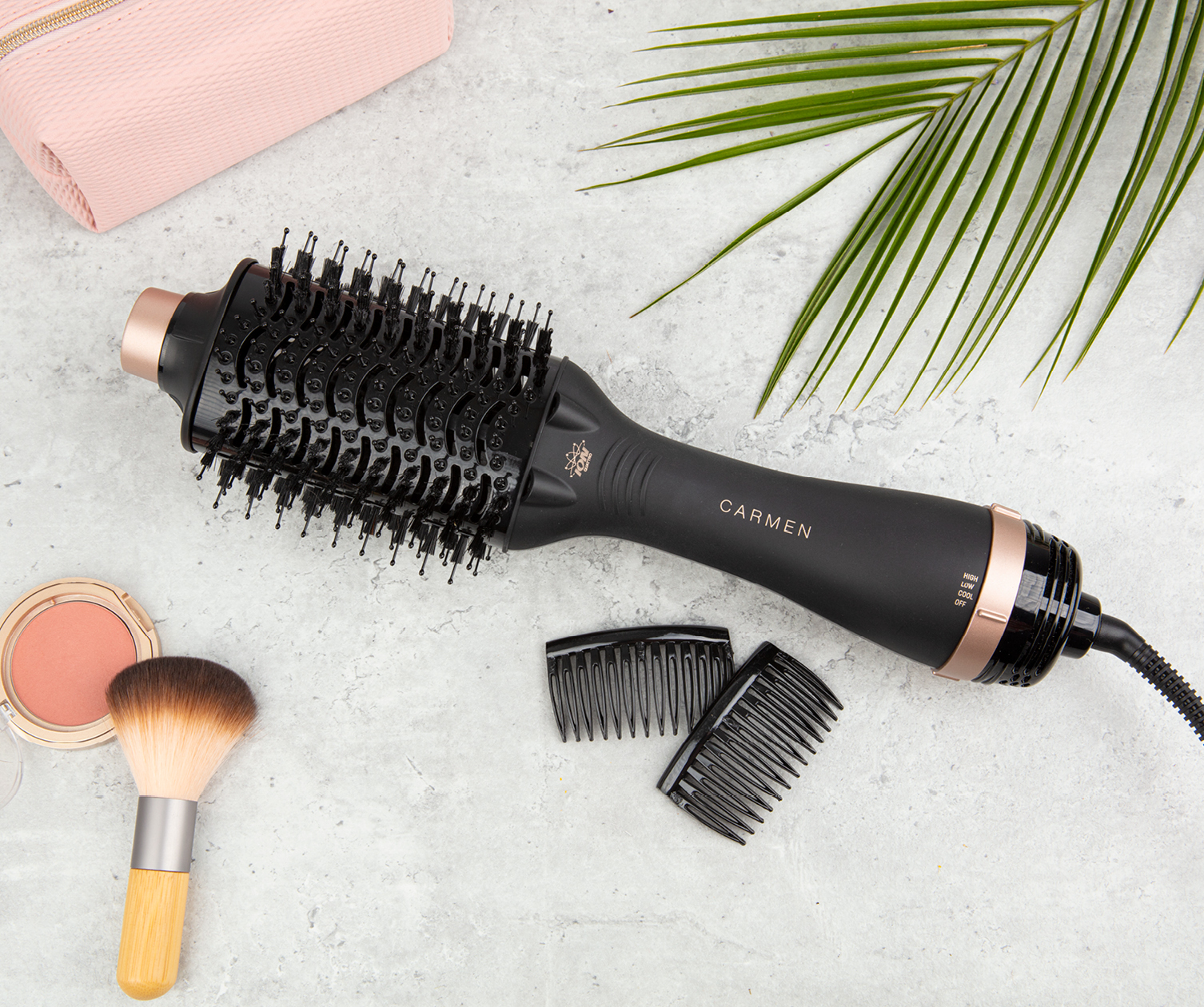 Black and rose gold hair styler, with combs and makeup brush on a white surface.