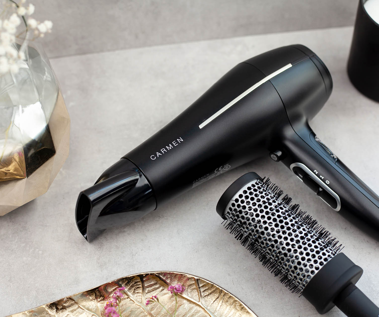 A black hair dryer with a brush and a decorative tray. It says CARMEN on the dryer.