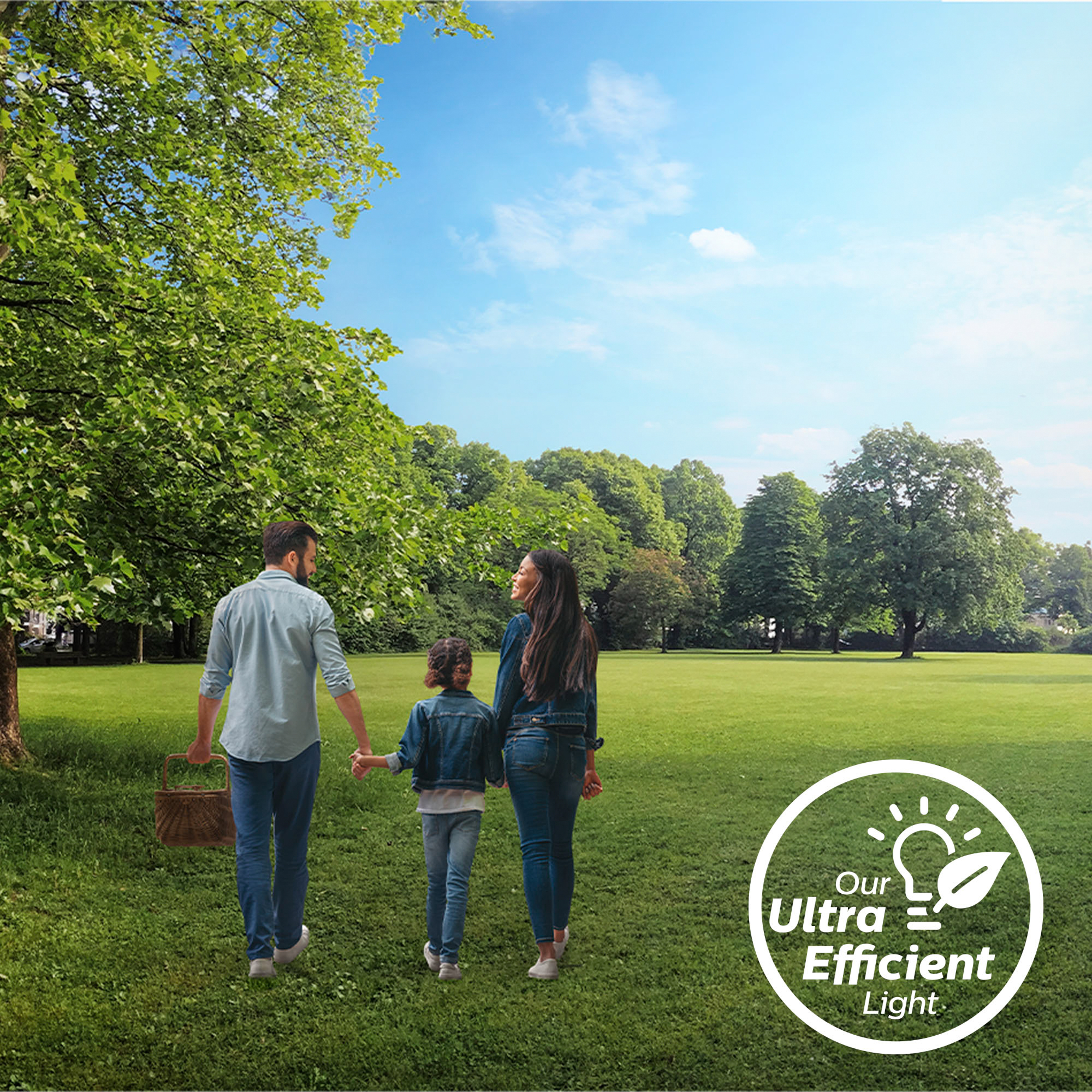 Familie geht mit einem Korb spazieren. Grünes Gras, Bäume und blauer Himmel im Hintergrund.