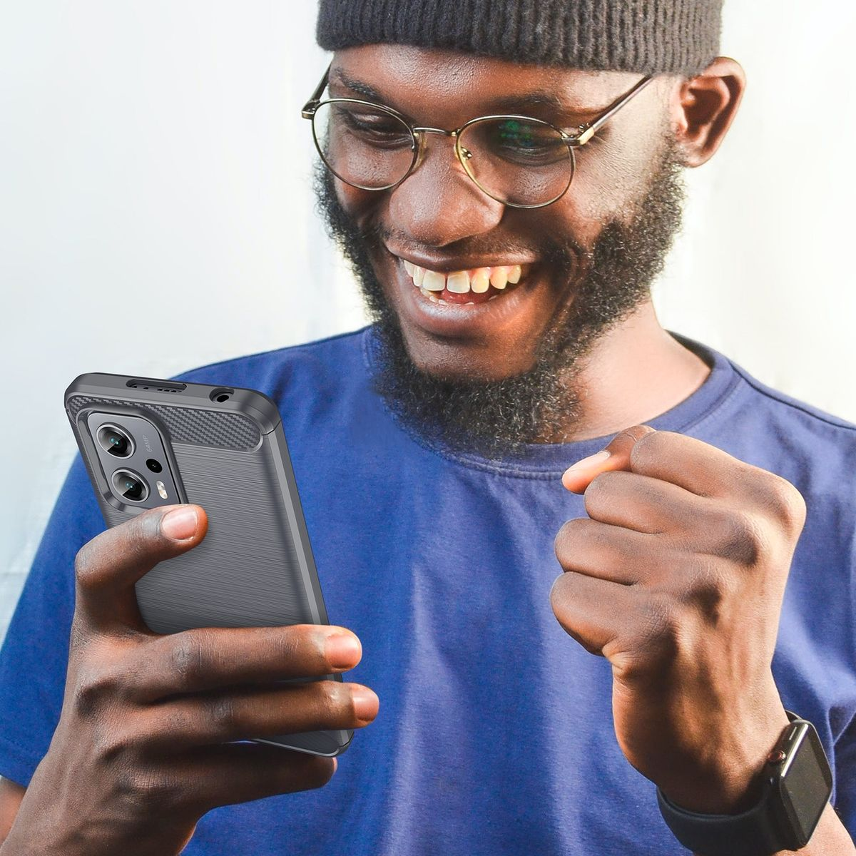 Ein Mann lächelt und hält ein Telefon mit Hülle. Die Handyhülle ist grau und hat ein Carbonfaser-Design.