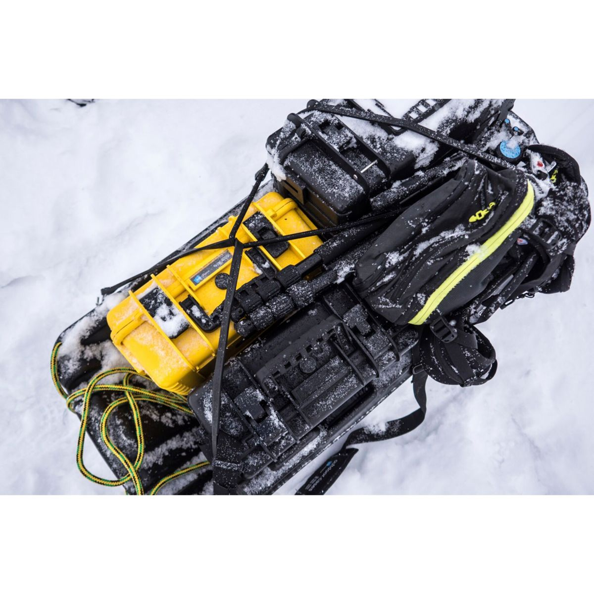 Schneebedeckter Schlitten mit gelben und schwarzen Koffern. Schnee Hintergrund.