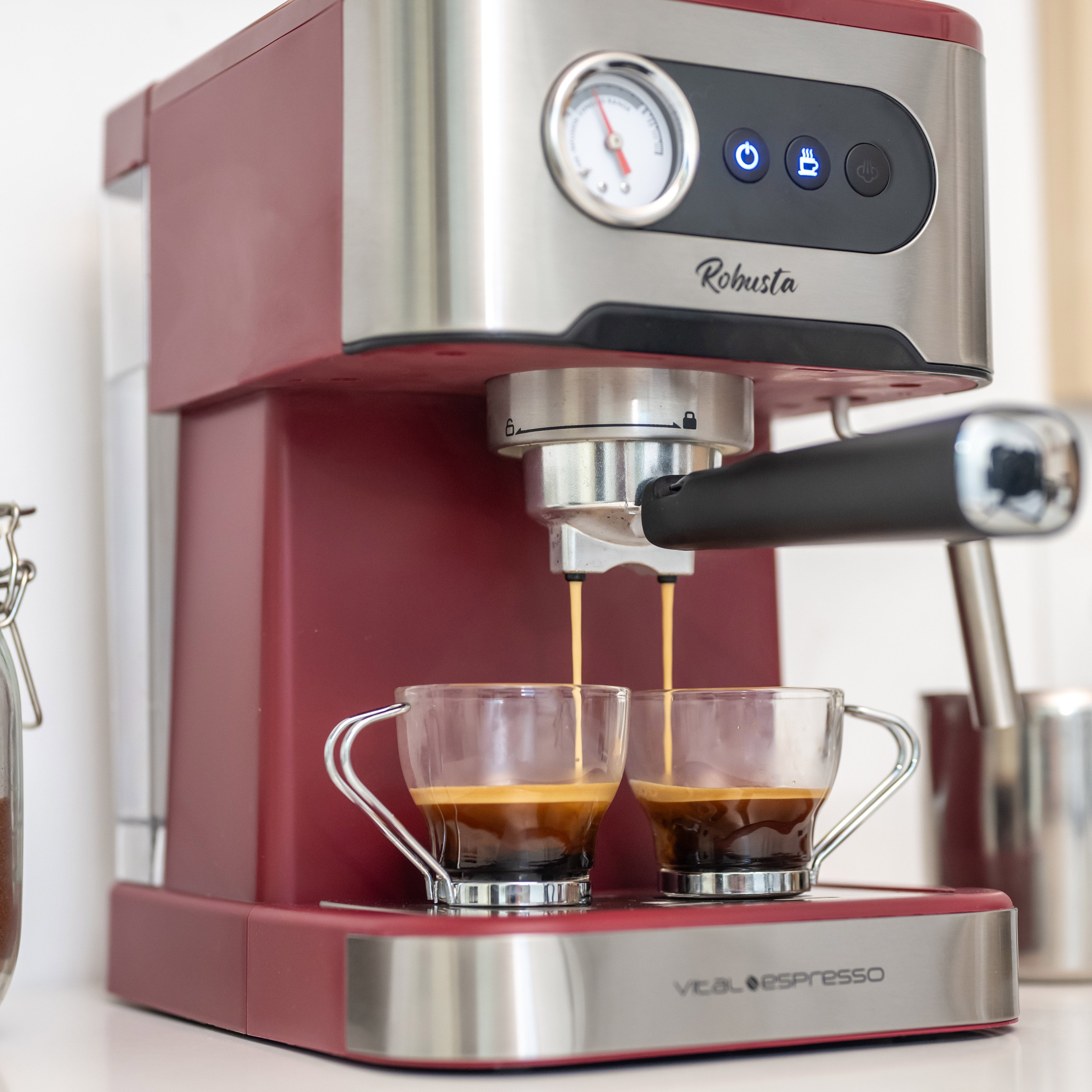 Una máquina de espresso que dispensa café en dos tazas de vidrio.