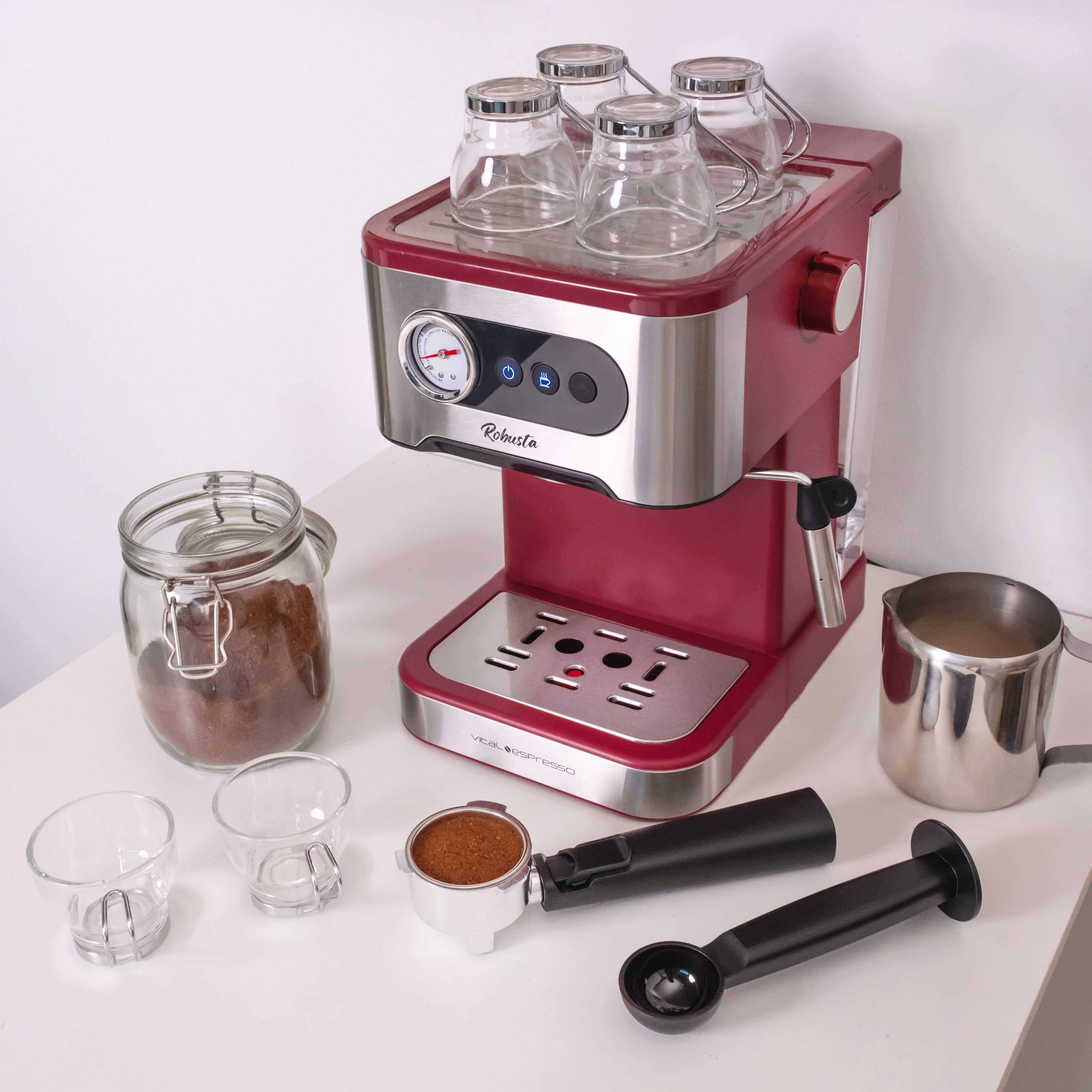 Máquina de espresso roja y plateada con accesorios. Incluye tazas, un molinillo de café y un espumador de leche.