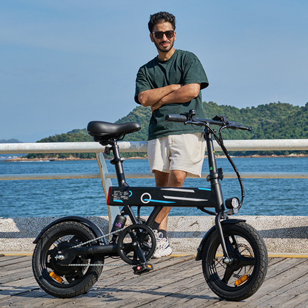 Ein Mann steht neben einem schwarzen E-Bike auf einem Holzsteg am Wasser. Er lächelt.