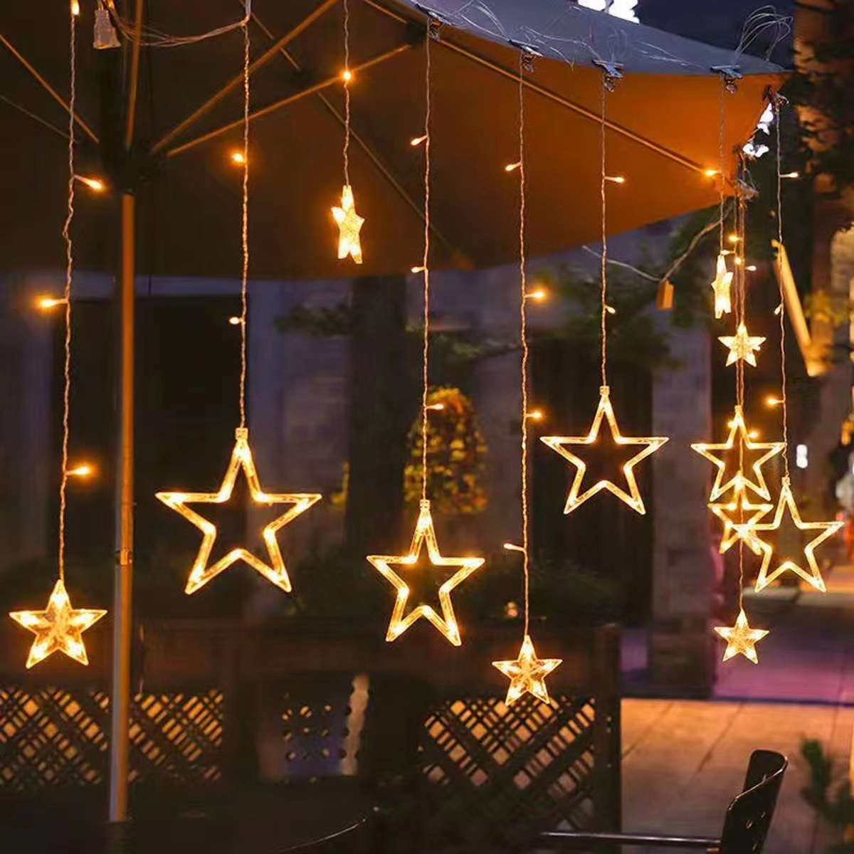 Lichterketten mit Sternformen. Einige Lichter sind auf einer Terrasse. Dunkler Hintergrund.