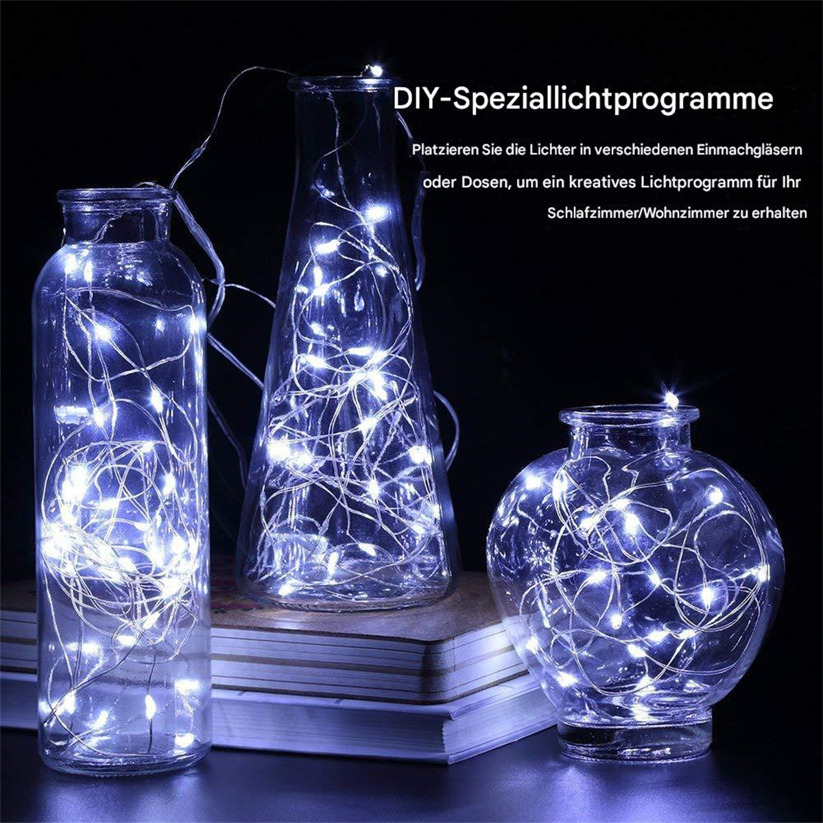 Drei Glasflaschen mit Lichterketten. Sie stehen auf einem Tisch mit einem Buch.