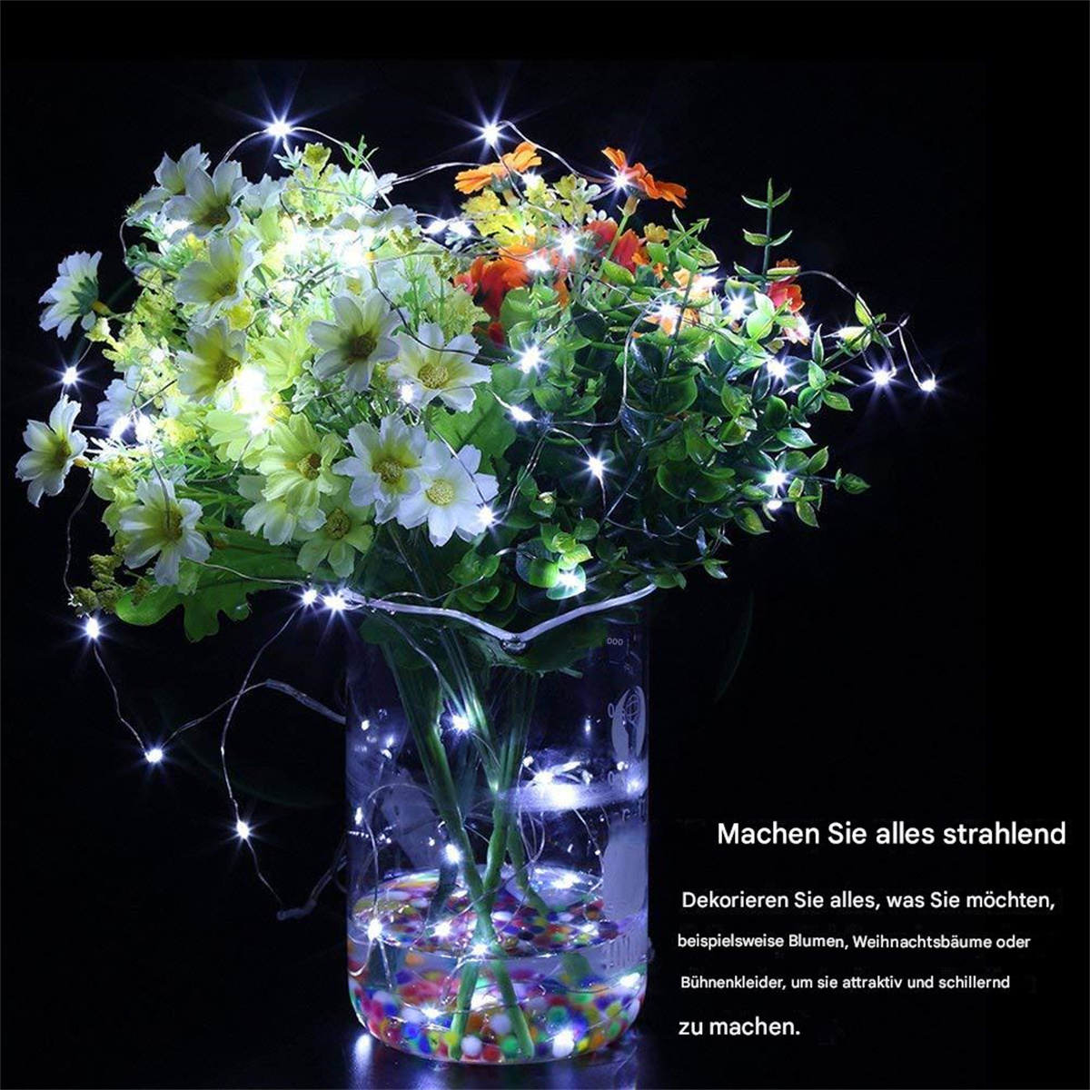 Blumen mit Lichterketten in einer Glasvase auf schwarzem Hintergrund.