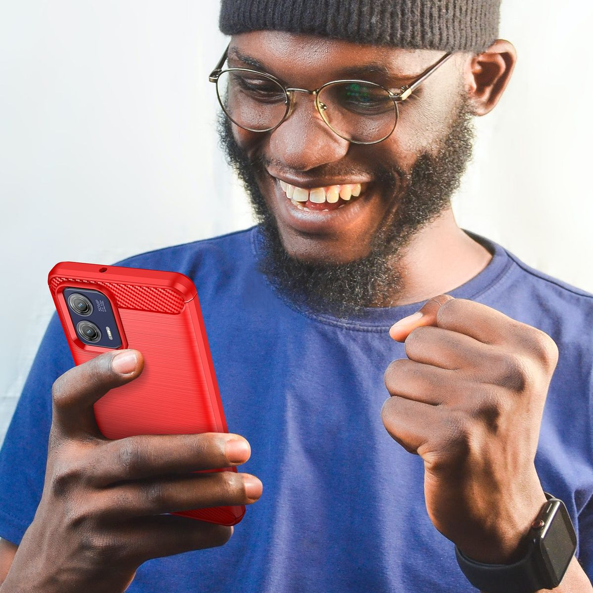 Mann lächelt, hält eine rote Handyhülle und schaut auf sein Telefon. Er trägt eine Brille.