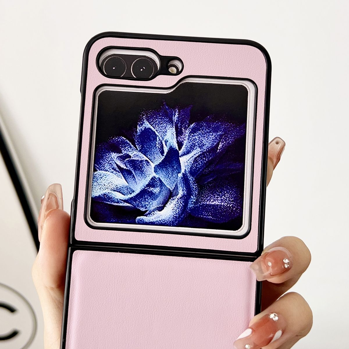 Nahaufnahme einer rosa Handyhülle mit floralem Design. Die Handyhülle ist geöffnet und ein Telefon befindet sich darin.