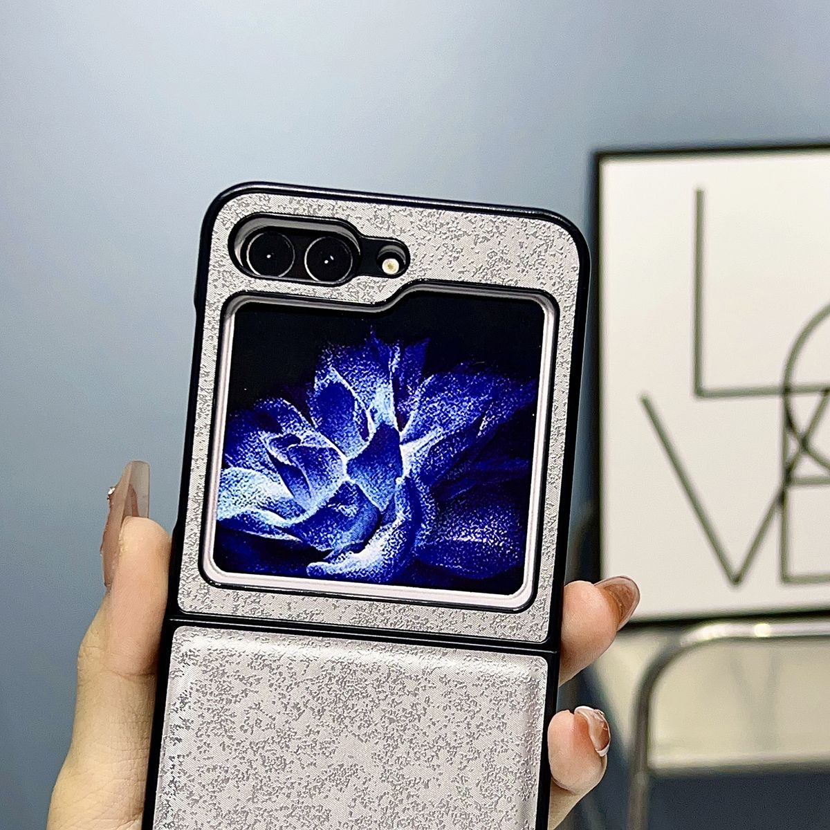 Eine Handyhülle mit floralem Design. Das Telefon ist geöffnet und zeigt eine blaue Blumenanzeige.
