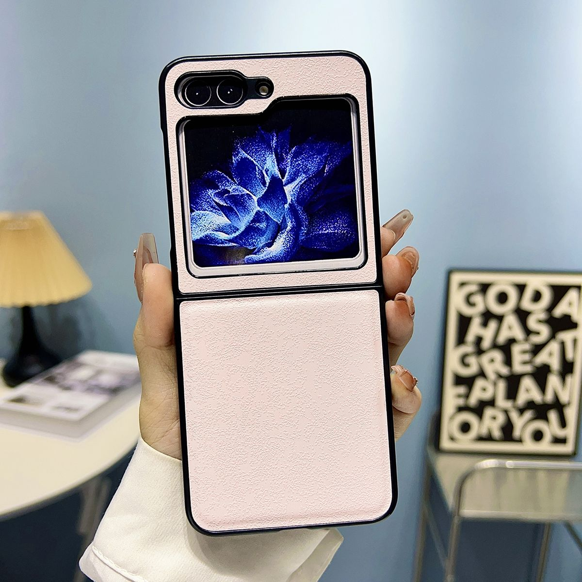 Eine Person hält eine rosa Handyhülle. Das Telefon ist geöffnet und zeigt eine blaue Blume.