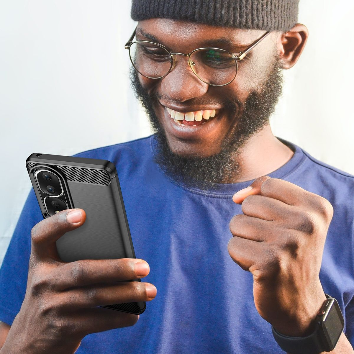 Ein Mann mit Brille und blauem Hemd hält ein Telefon und lächelt.