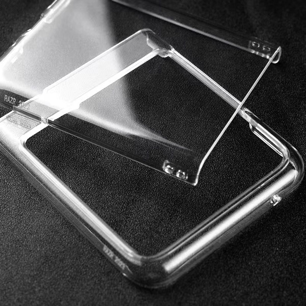 Transparente Handyhülle, bestehend aus zwei Teilen, die sich auf dunkler Oberfläche überlappen.