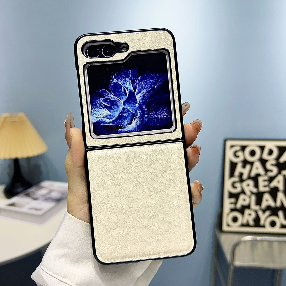 Eine cremefarbene Handyhülle ist geöffnet und zeigt ein Telefon. Die Hülle wird von einer Hand gehalten, blauer Hintergrund.