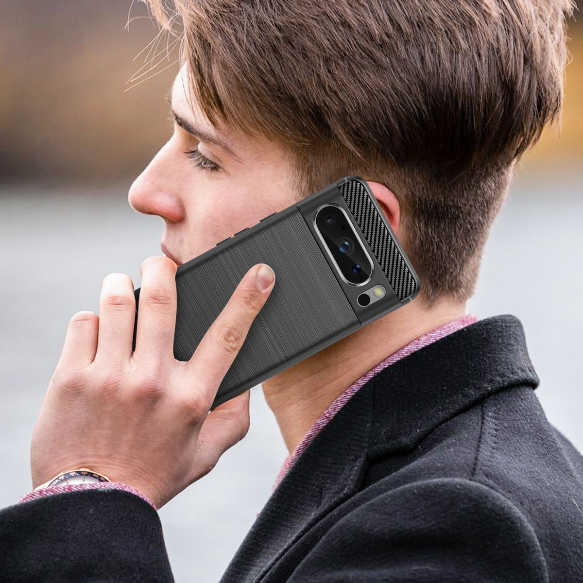 Ein Mann hält ein Telefon in einer schwarzen Hülle an sein Ohr, im Freien.