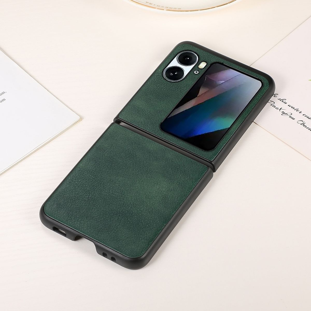 Grüne Klapphandy-Hülle, offen, mit sichtbarem Telefon, auf heller Oberfläche.