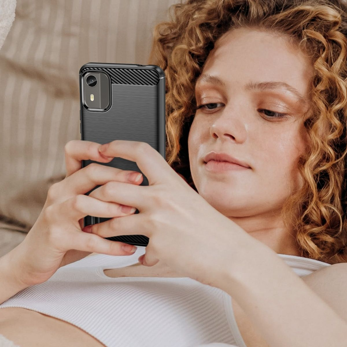 Eine Frau hält ein schwarzes Telefon. Das Telefon hat eine Kameraausbuchtung und ein Kohlefaserdesign.