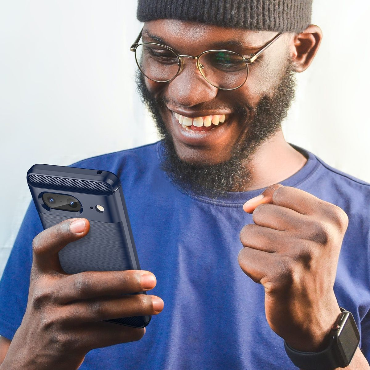 Ein Mann mit Brille hält ein Telefon mit dunkelblauer Hülle und lächelt breit in die Kamera.