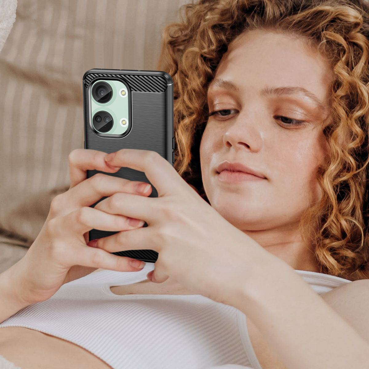 Frau mit lockigem Haar hält ein Telefon in einer schwarzen Hülle. Weißer Hintergrund.
