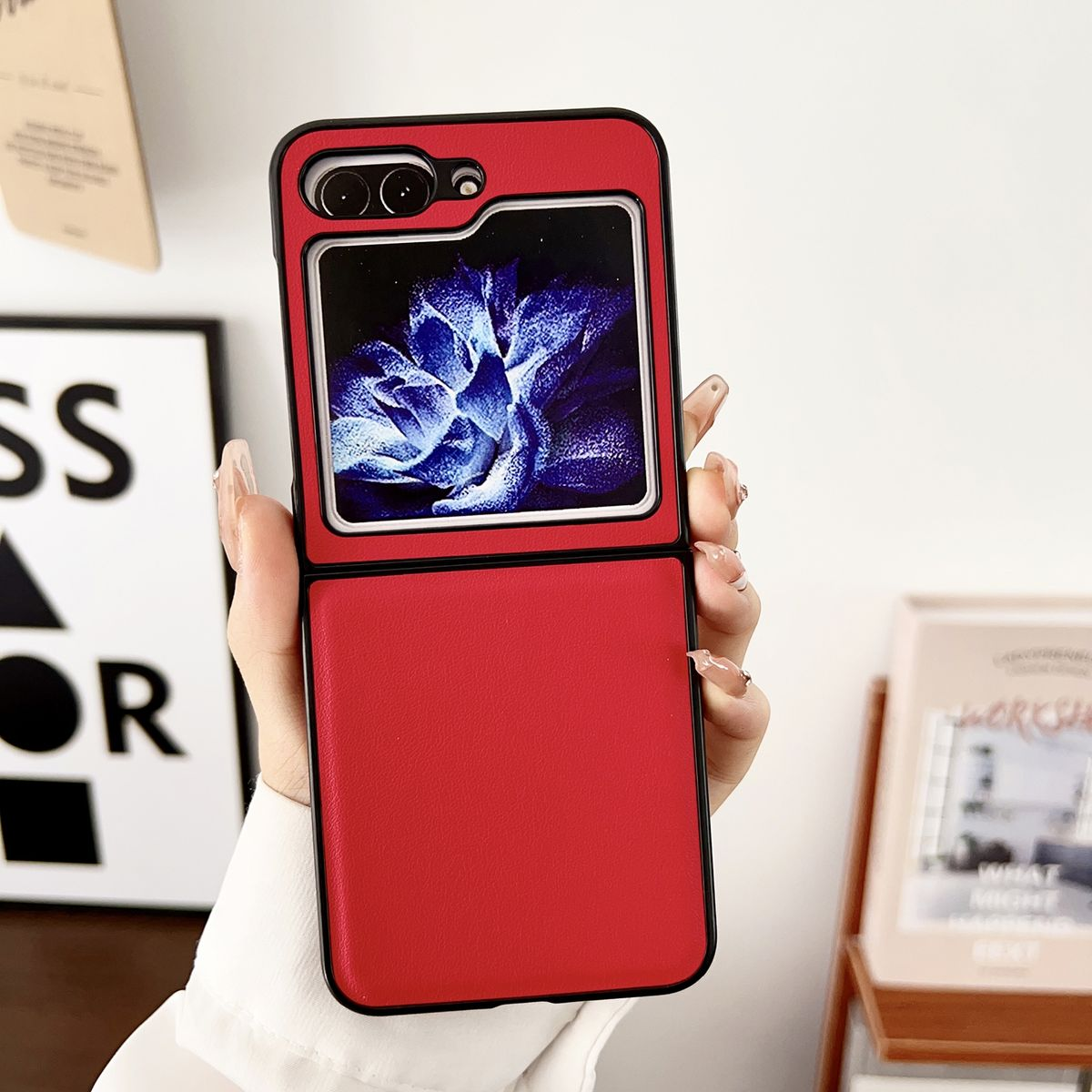 Eine Person hält eine rote Handyhülle mit einem Telefon, das ein blaues Blumenbild zeigt.