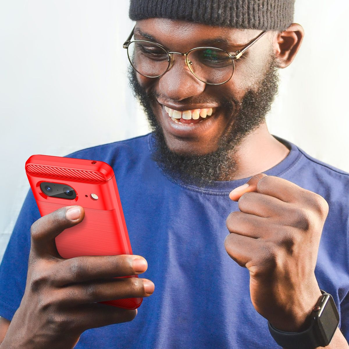 Ein lächelnder Mann mit Brille hält eine rote Handyhülle, ein Telefon zeigend. Er trägt ein blaues T-Shirt.