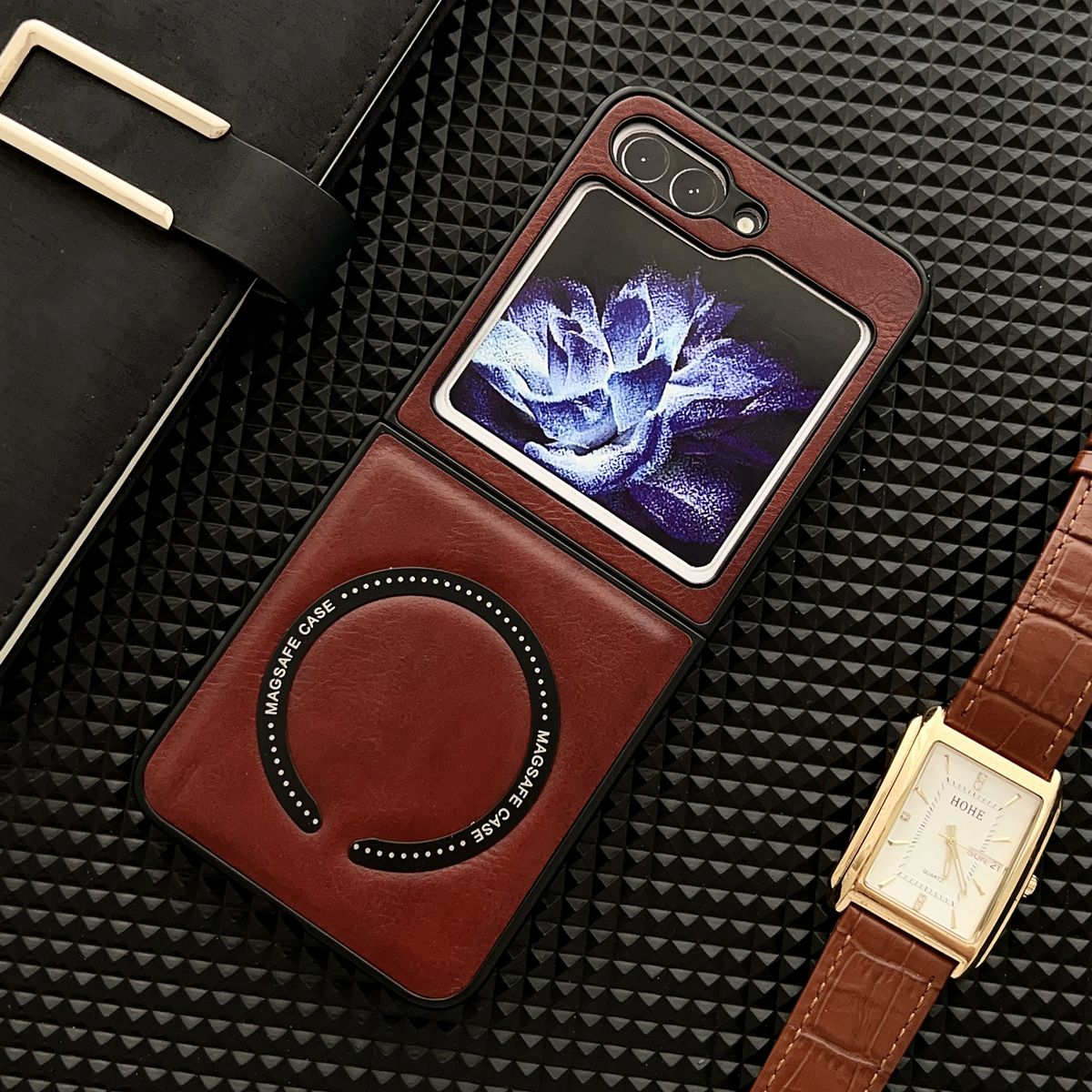 Geöffnete Handyhülle mit Telefonbildschirm. Die Hülle ist rot, im Hintergrund eine Uhr und Notizbuch.