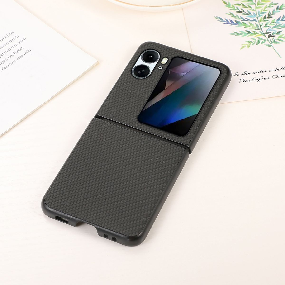 Schwarze Handyhülle mit Carbonfaser-Textur, Telefon ist offen und zeigt ein Bild. Auf einer Oberfläche platziert.