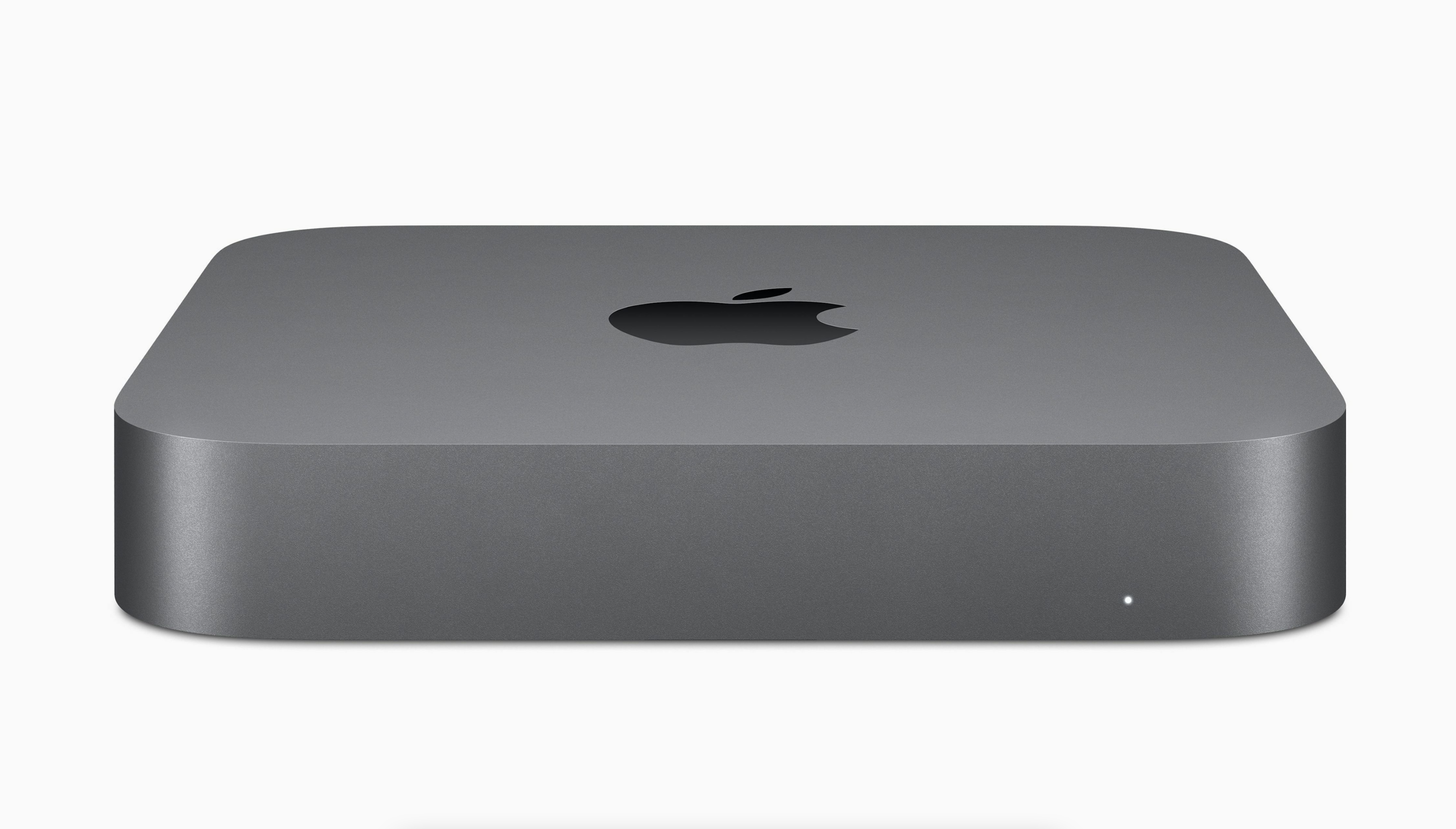 Szare urządzenie Apple Mac Mini leżące na białej powierzchni.
