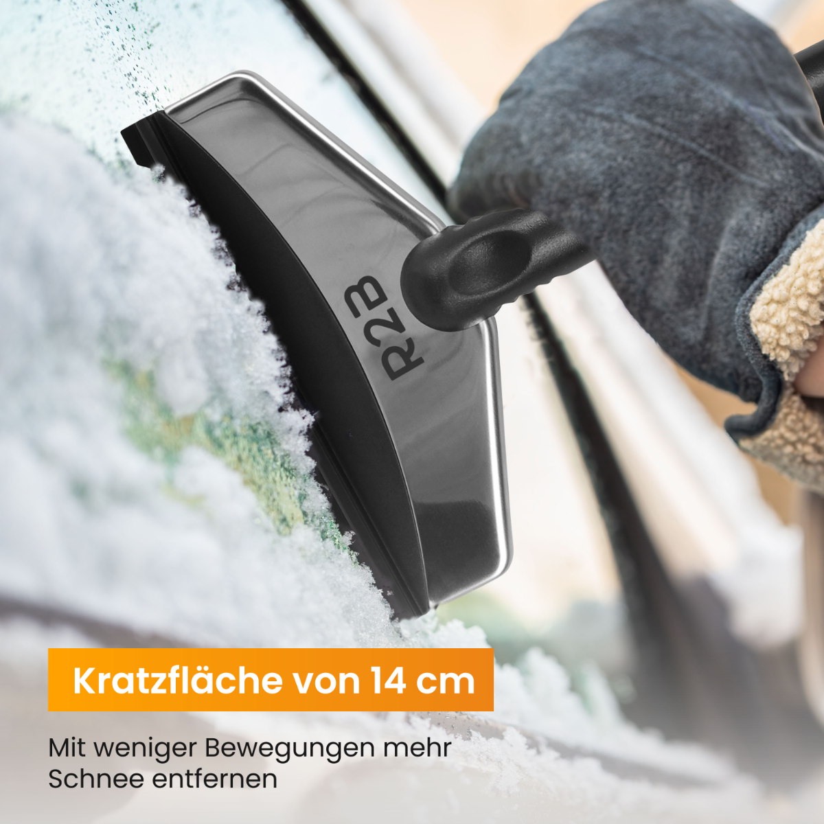 Een hand gebruikt een zwarte ijskrabber op een autoruit bedekt met sneeuw. De schraper heeft de tekst 'R2B'.